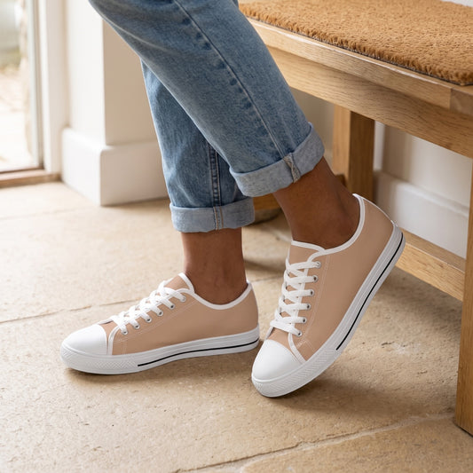 Sand Ladies' Two-Tone Low Top Sneakers. Lifestyle scene: Dune-side coastal cottage entry; sandy beige stone kept clean, raw oak bench, woven mat