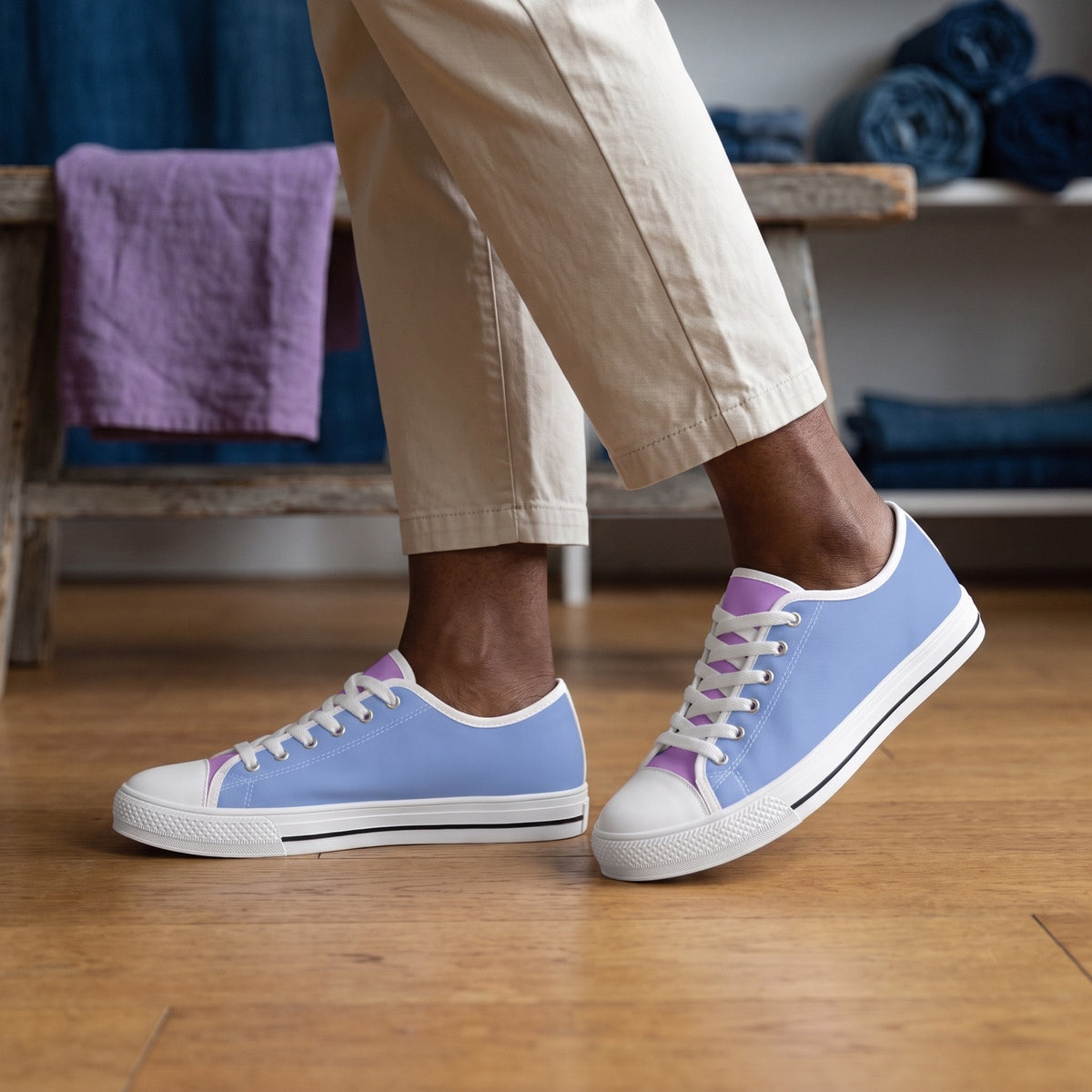 Purple Daze Ladies' Two-Tone Low Top Sneakers. Lifestyle scene: Indigo-dyed textile studio; warm oak floor, violet linen swatch folded on bench, soft north light