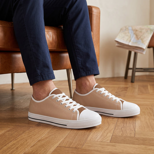 Sand Men's Two -Tone Low Top Sneakers — A boutique desert inn reading room in the afternoon, a close view of a man relaxing in a cognac leather chair.