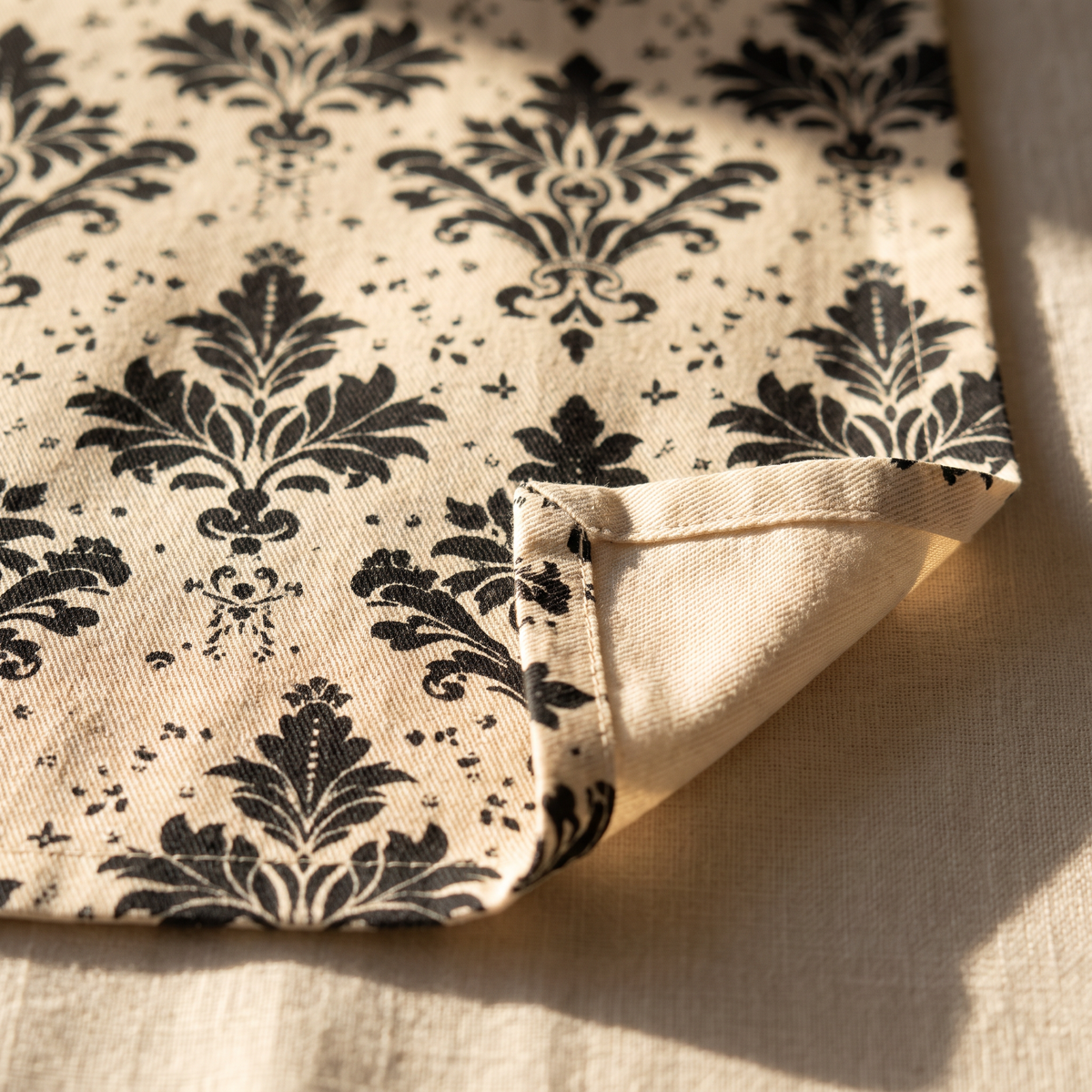 Classic Regency napkin close-up: cotton twill weave, hemmed edge, and a small plain natural cotton reverse reveal showing the one-sided print