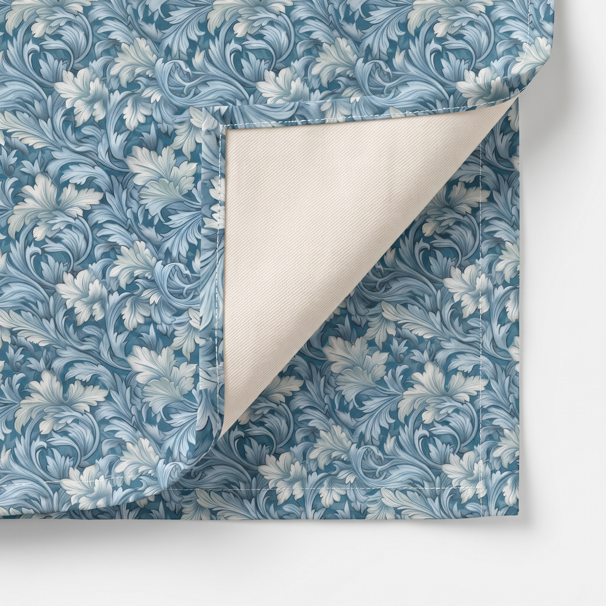 Close-up of Soft Blue Leaf Tapestry napkin corner folded back showing cream twill backside and hem